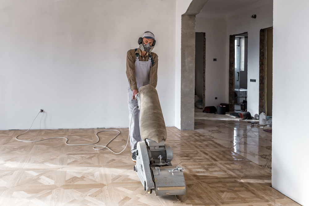 A carpenter using a machine to fix the hardwood floors during the installation process in Long Island